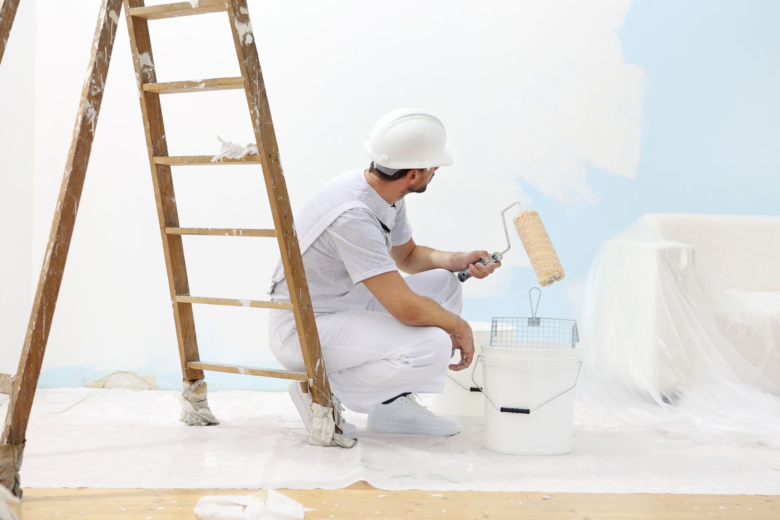 pintor con un rodillo pintando con pintura plastica blanca